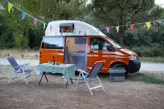 Fourgon aménagé dans un champ avec des chaises de camping